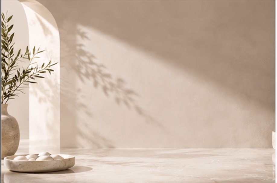 A plaster arch, an olive branch in a stone vase, and a dish of pale pebbles.