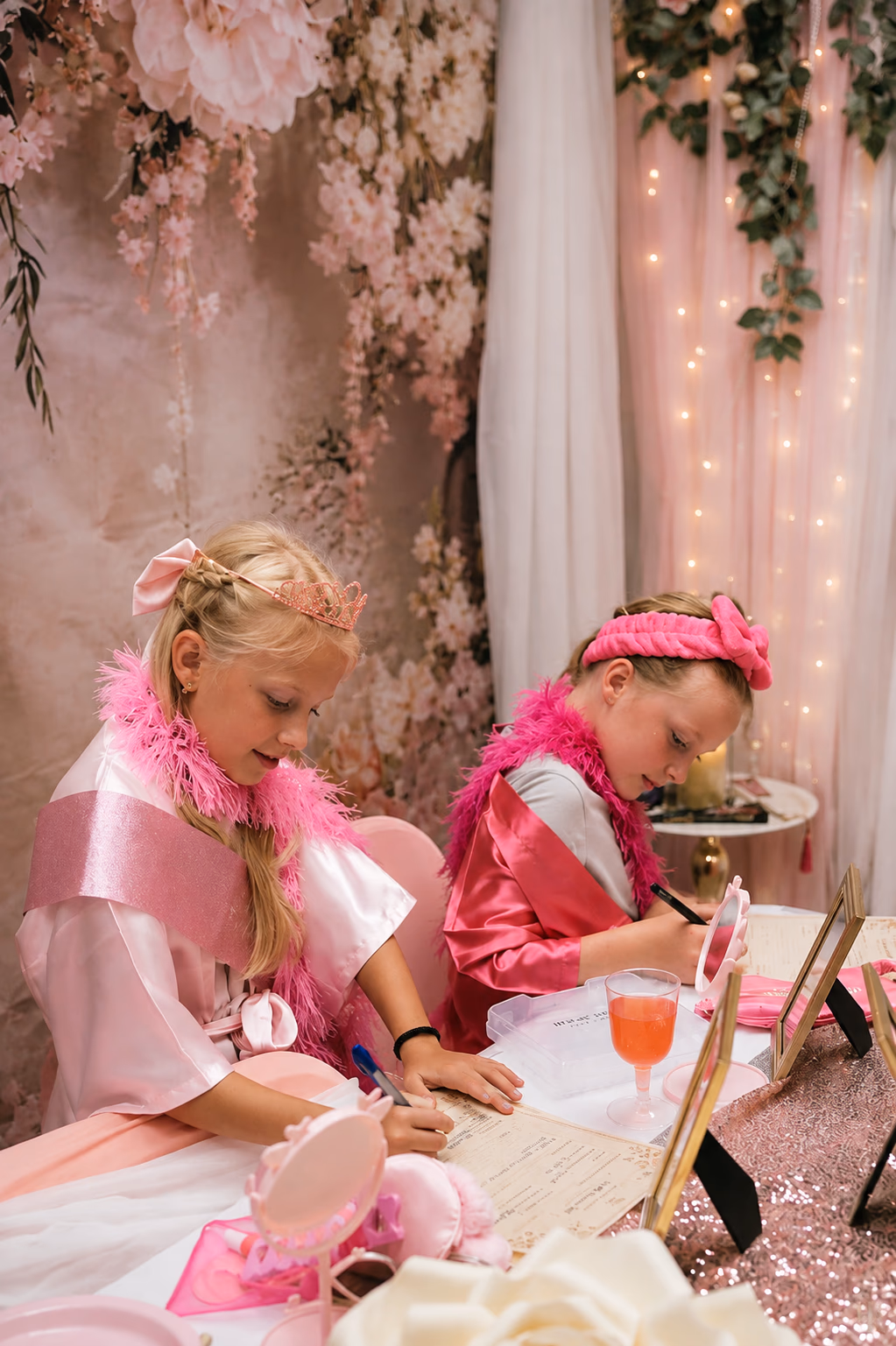Two children in pink event robes working on a creative activity at the styled Little Roses table.