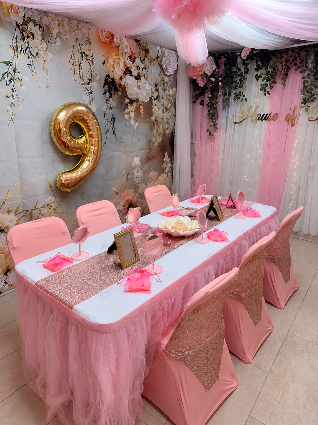 Five children gathered around the styled pink party table beneath twinkle lights and the Little Roses butterfly wall.